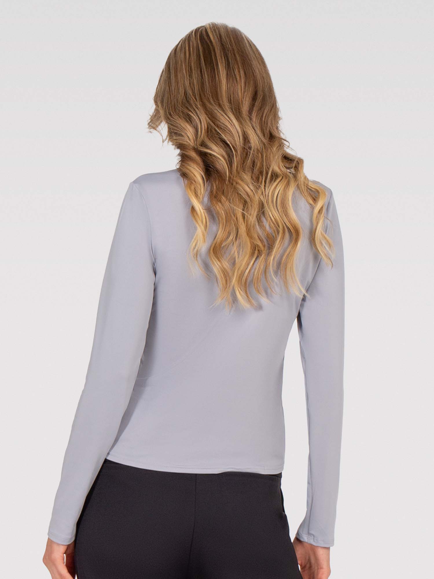 Back view of model wearing the Riley performance mock neck in deep pearl by inPhorm NYC withher hands at her side