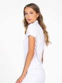 Side view of model wearing the Riley performance short sleeve polo in white by inPhorm NYC with her hands at her side