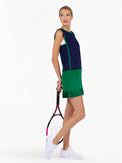 Side view of model wearing the Sinclaire pleated golf and tennis skirt in ivy by inPhorm holding a tennis racket