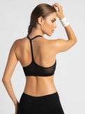 Back view of model wearing the classic strappy bra in black by inPhorm NYC with her hand at the top of her head