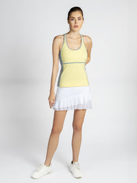 Front view of model wearing the Ashley racer tank in lemondae and pearl by inPhorm NYC wearing a white skirt and white shoes